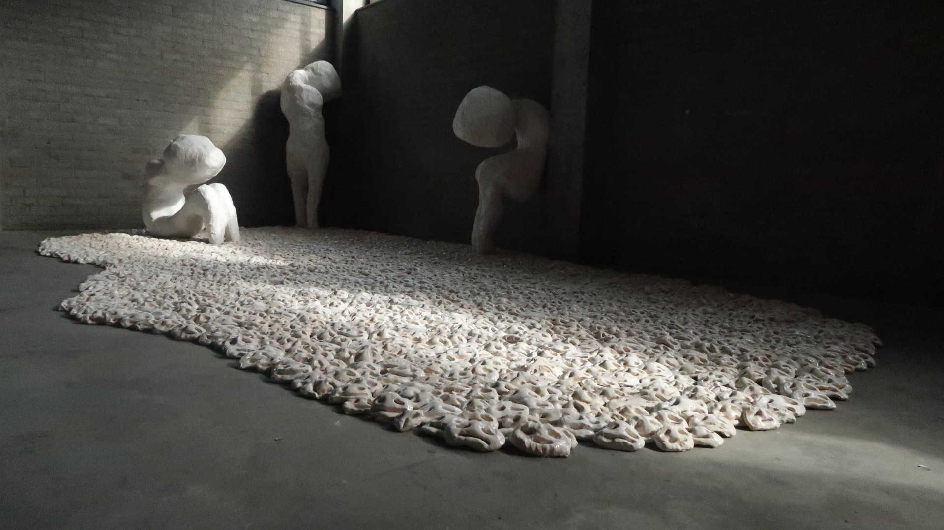 Collective Loneliness, 2023, Ceramic installation of 2700 individual faces and plaster sculptures